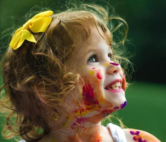 A paint-splattered young girl smiling